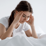 A tired and sleep-deprived woman sitting at a desk, showcasing the effects of inadequate sleep on health and well-being