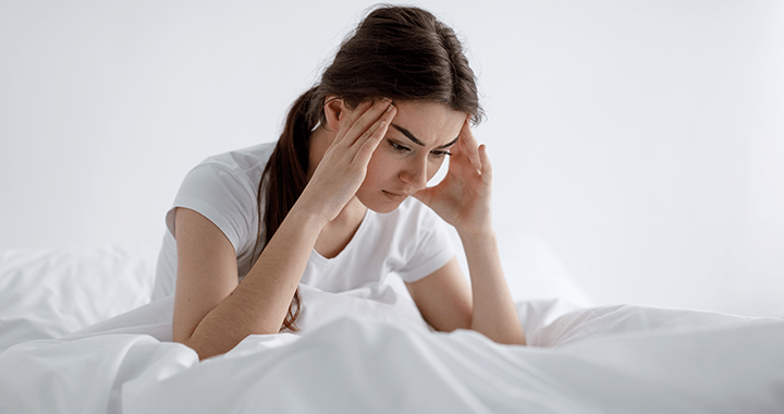 A tired and sleep-deprived woman sitting at a desk, showcasing the effects of inadequate sleep on health and well-being